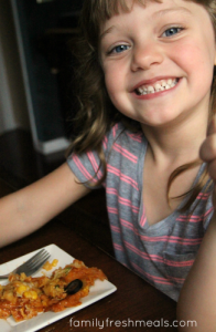 Child sitting with a plate of casserole