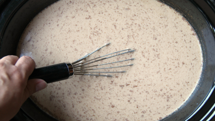 whisking ingredients for pumpkin latte in a slow cooker