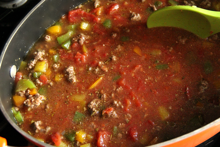 Tomatoes with juice, broth, tomato sauce, soy sauce and Italian seasoning being stirred in to pan