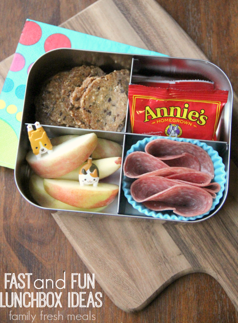 Crackers fruit snacks, apples and some salami packed in a small metal lunchbox