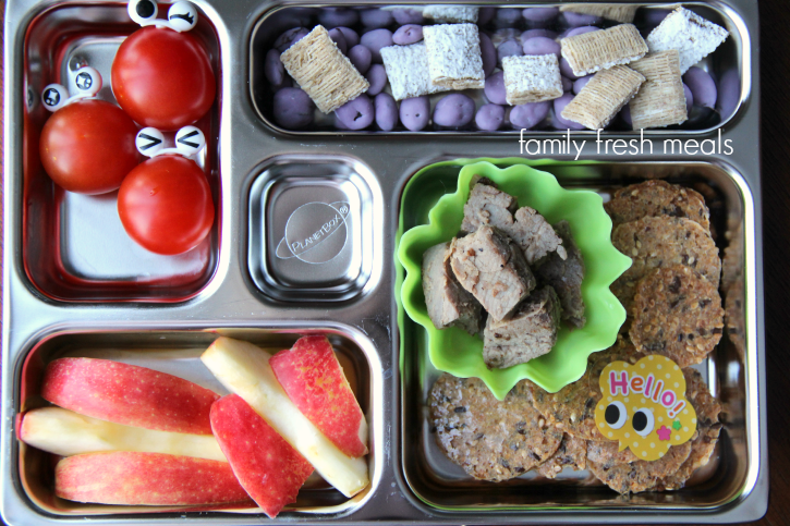 Steak, crackers, yogurt raisins & cereal, cherry tomatoes and apples packed in a metal lunchbox