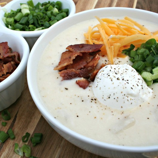 Baked Potato Soup in a bowl, topped with shredded cheese chopped bacon, sour cream and chives