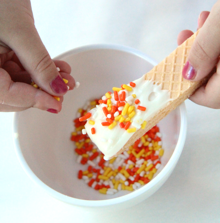 Adding Halloween themed sprinkles to the top of the wafer cookie