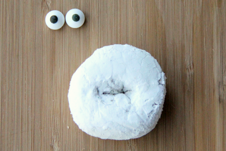 2 candy eyes next to a powdered donut