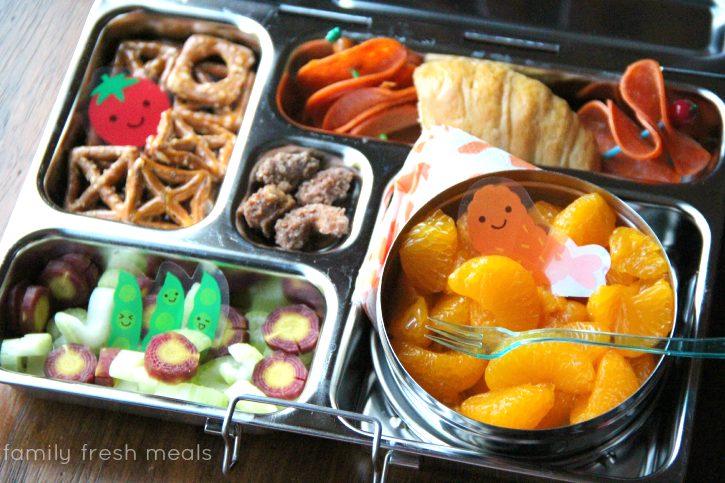 Fresh fruit, veggies, croissant packed in a metal lunchbox