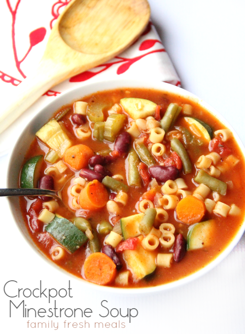 Minestrone Soup in a white bowl with a wooden spoon next to it