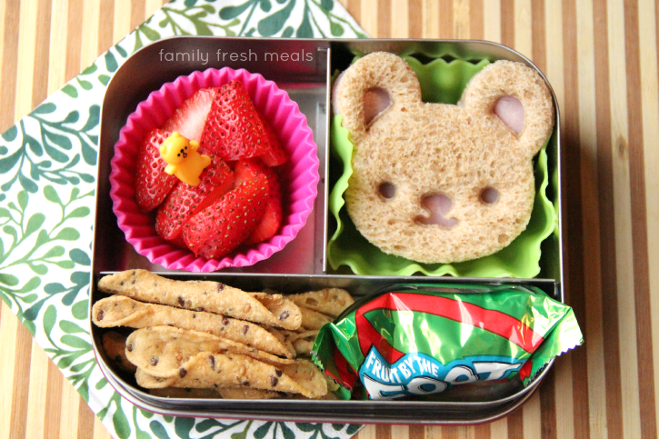 bear shaped sandwich, strawberries, tortilla chips and fruit snack packed in a metal lunch box