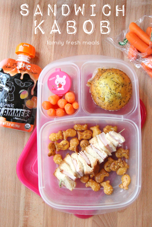 Sandwich kabob, carrots, container of dip, fish shaped  pretzels, a poppy seed muffin and a Slammers power smoothie pouch - packed in a plastic lunchbox