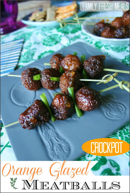 Orange glazed crockpot meatballs on skewers, on a blue plate