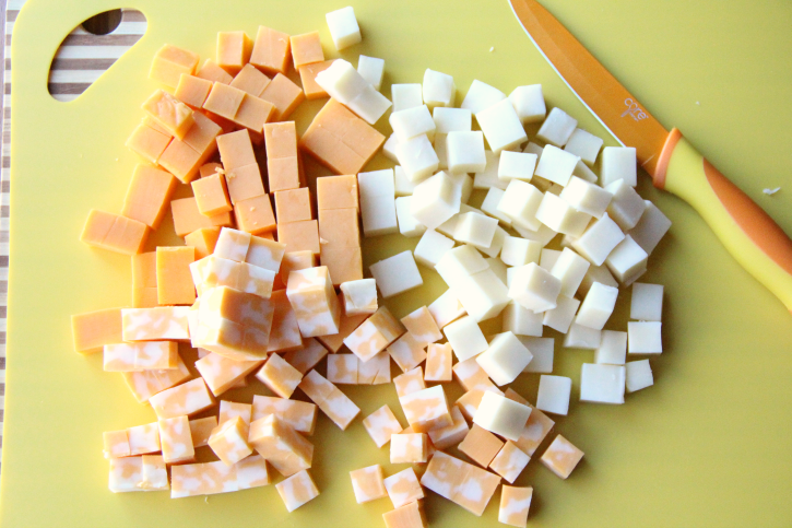 cheese cut into small cubes on a cutting board