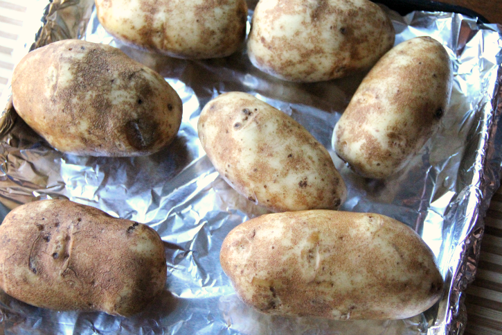 7 baking potatoes on a foil lined baking sheet