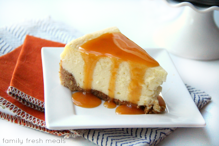 Slice of White Chocolate Cheesecake with Almond Crust on a white plate with caramel sauce drizzled on top