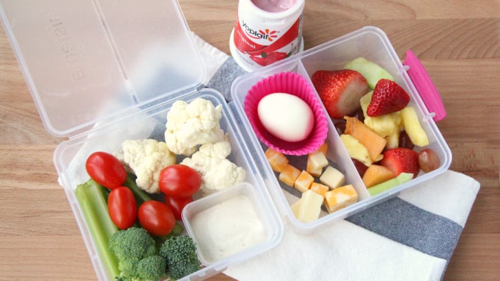 fruit, vegetables, dip, cheese and a hard boiled egg packed in a plastic lunch box