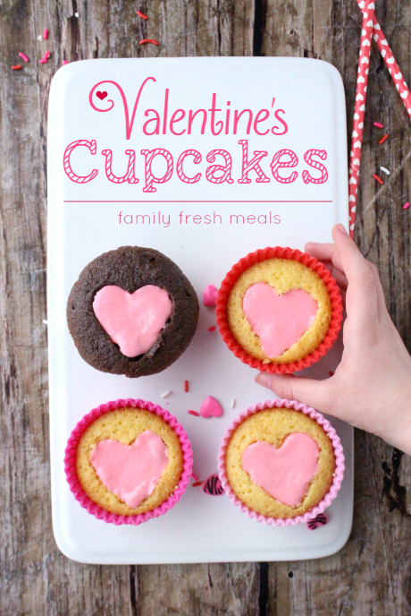 Four Easy Heart Valentine Cupcakes on a white plater, with a hand grabbing one