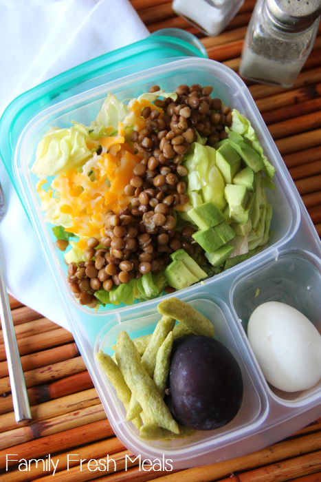 Salad with lentils, avocado and cheese packed in a plastic lunch box