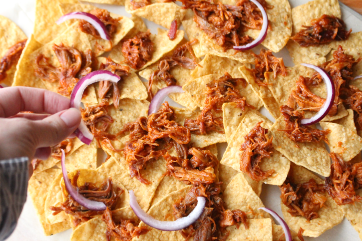 adding sliced red onions to nachos