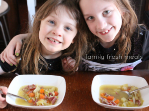 Two girls sitting with bowls of soup