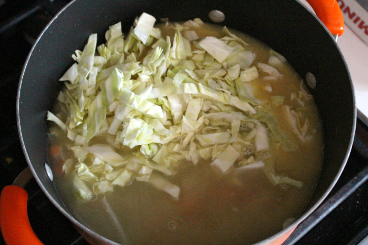 chicken broth cabbage and potatoes being added to soup pot