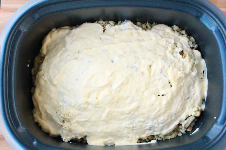 Creamy mixture placed on top of stuffing in slow cooker
