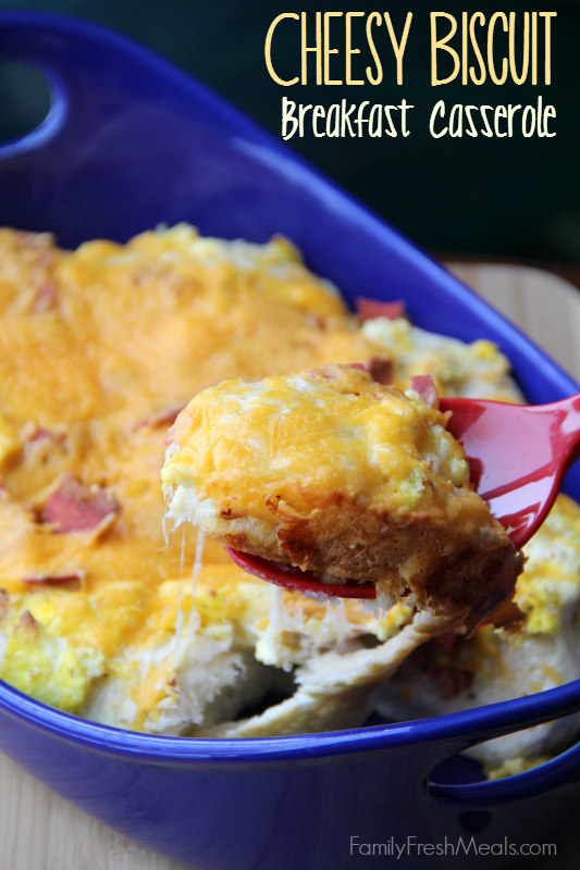 Cheesy Biscuit Breakfast Casserole in a blue baking dish , with a serving spoon scooping some up