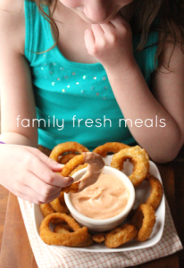 Child dipping an onion ring into Copycat Outback Blooming Sauce 