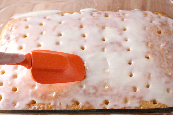 spatula spreading condensed milk over cake