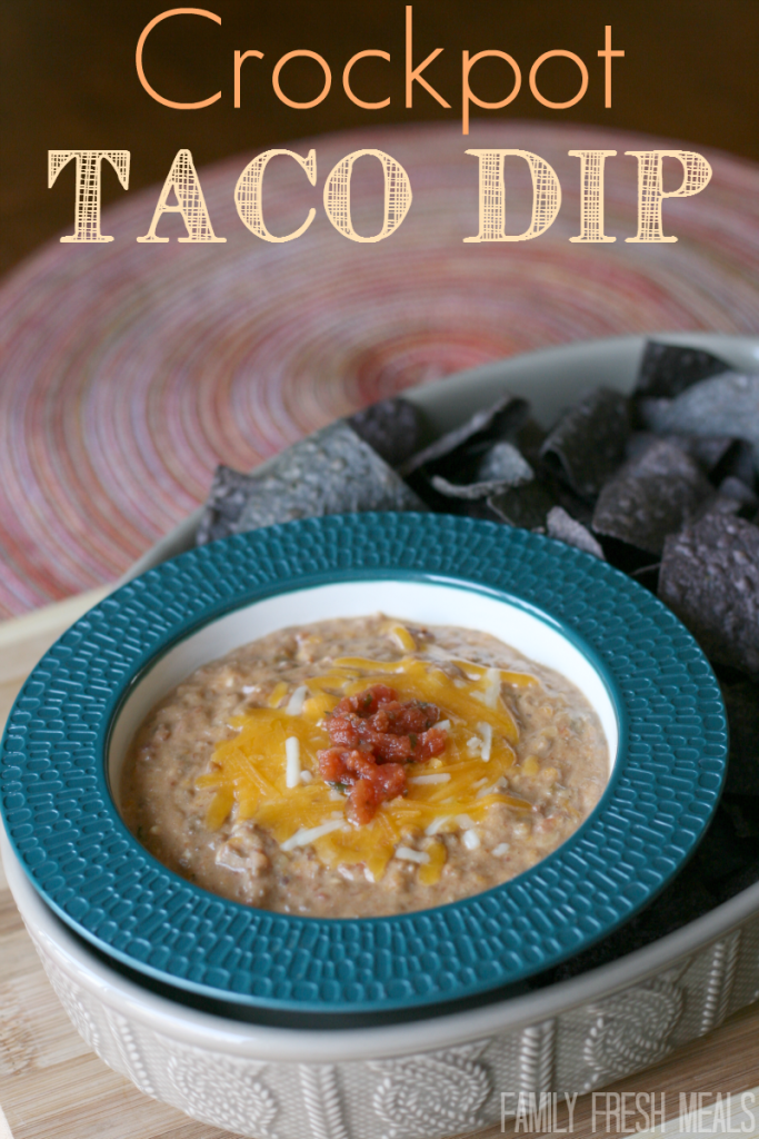 Cheesy Crockpot Taco Dip in a bowl with a side of blue tortilla chips