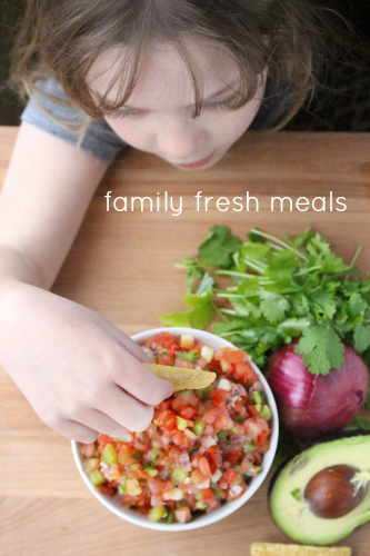 child scooping up some salsa with a chip