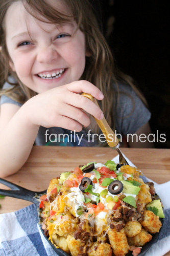 Child sitting with skillet of Tater Tot Nachos