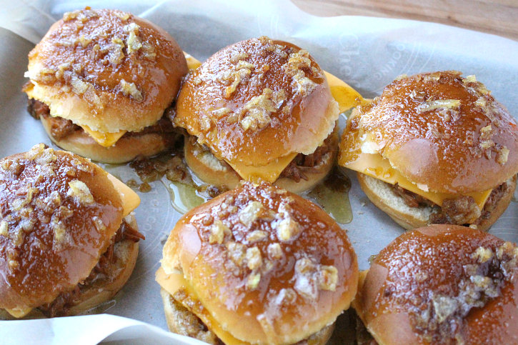 Baked BBQ Pork Sandwiches on a baking sheet topped with butter/onion mixture