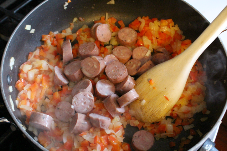 stirring sausage, peppers and onions in a large skillet