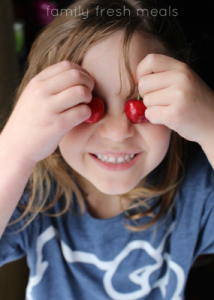 child holding cherries up to eyes