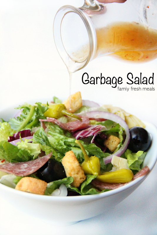 Garbage Salad in a serving bowl with dressing being poured over it