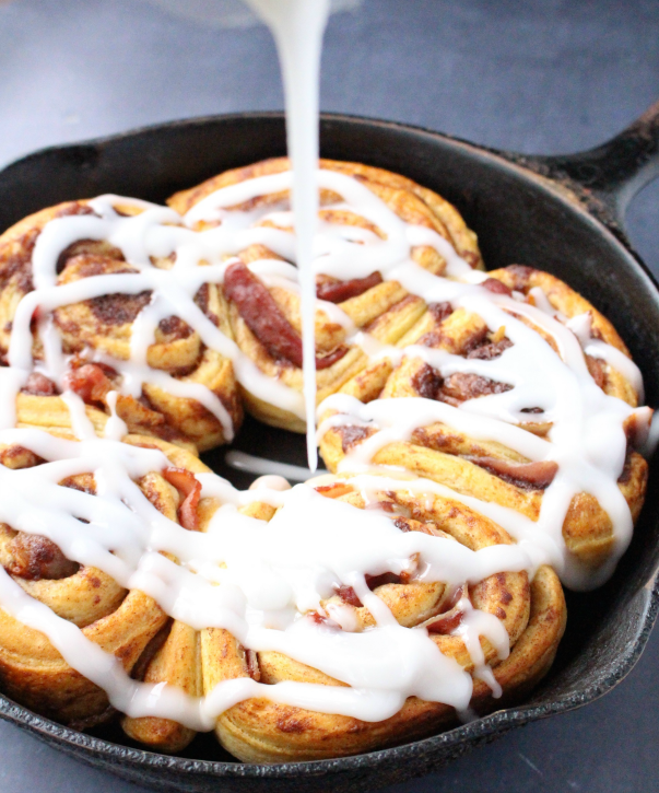 Drizzling icing over  Bacon Wrapped Cinnamon Rolls