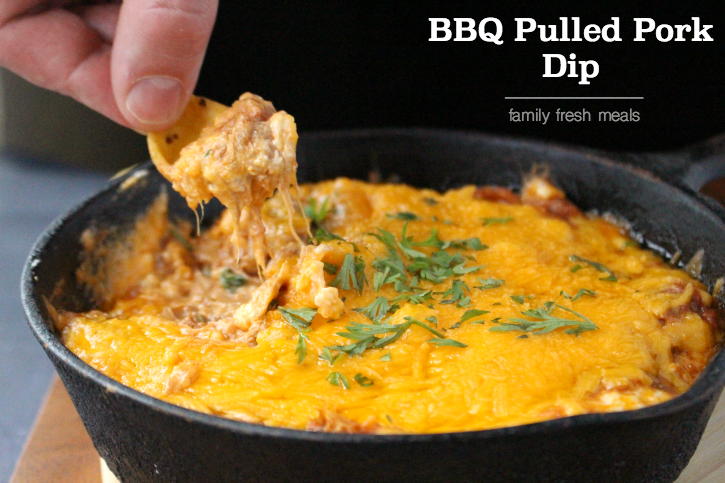 Tortilla chip scooping up Cheesy BBQ Pulled Pork Dip 