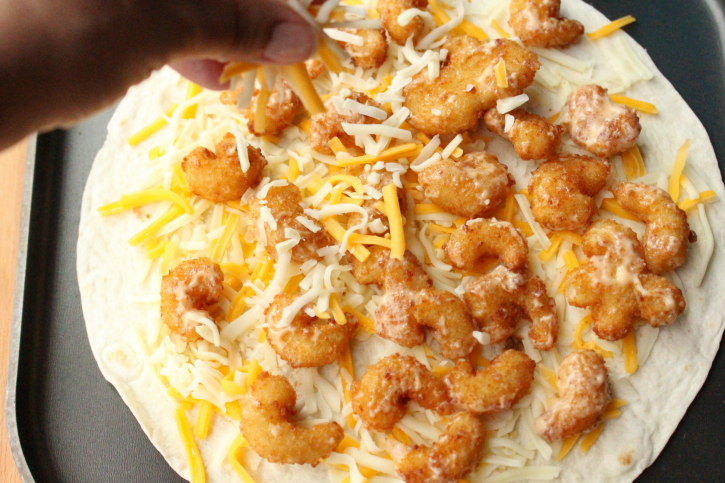 firecracker shrimp on a flour tortilla, topped with shredded cheese
