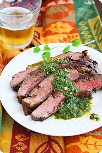 Grilled Marinated Flank Steak with Chimichurri Sauce on a white plate