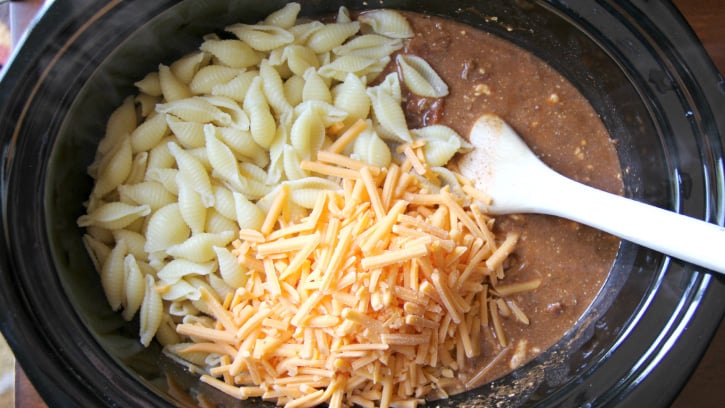 Easy Crockpot Taco Pasta Bake - Cooked pasta and shredded cheese added to slow cooker