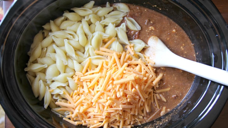 Easy Crockpot Taco Pasta Bake - Cooked pasta and shredded cheese added to slow cooker