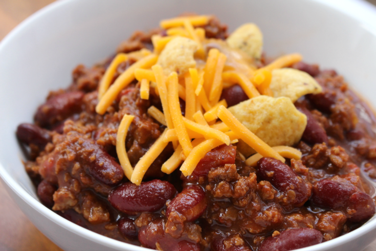 Easy Crockpot Chili - Chili in a white bowl topped with shredded cheese