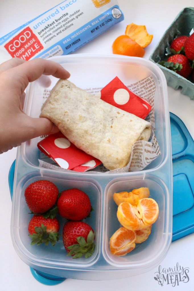 Breakfast burrito and fruit packed in a plastic lunchbox