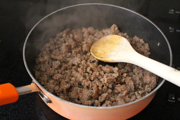 Biscuits and Gravy Breakfast Casserole - Browning sausage in a pan