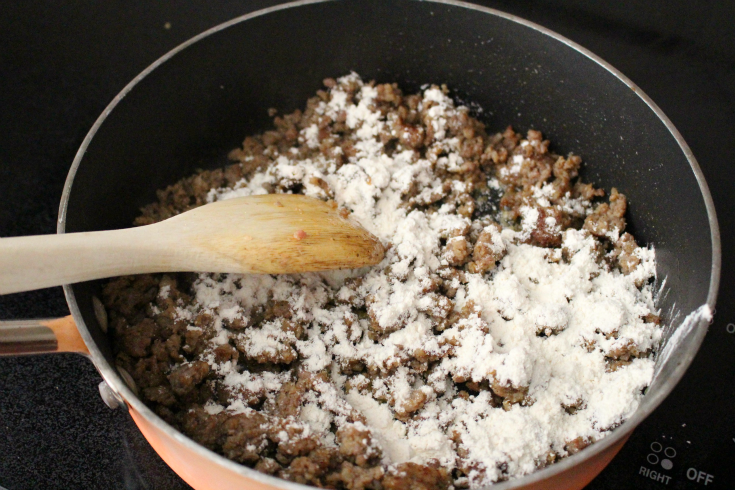 Biscuits and Gravy Breakfast Casserole - flour mixture sprinkled over browned sausage