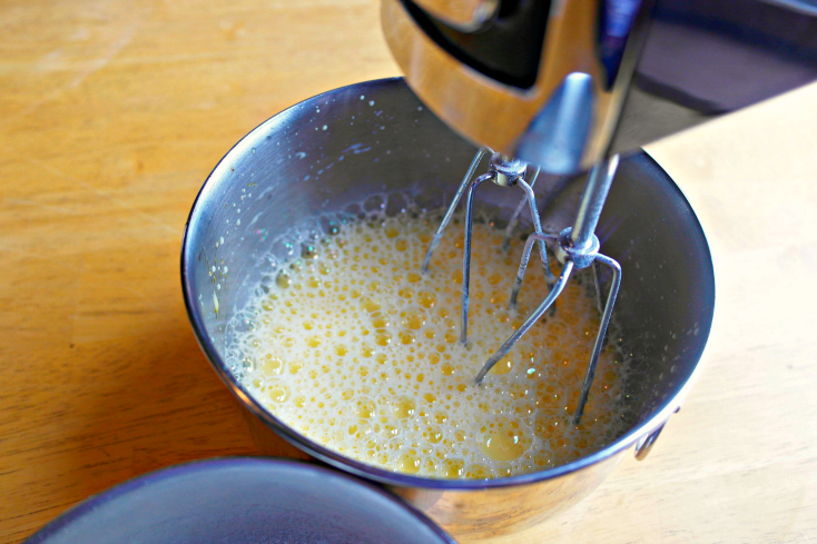 mixing together eggs and cream cheese with a mixer