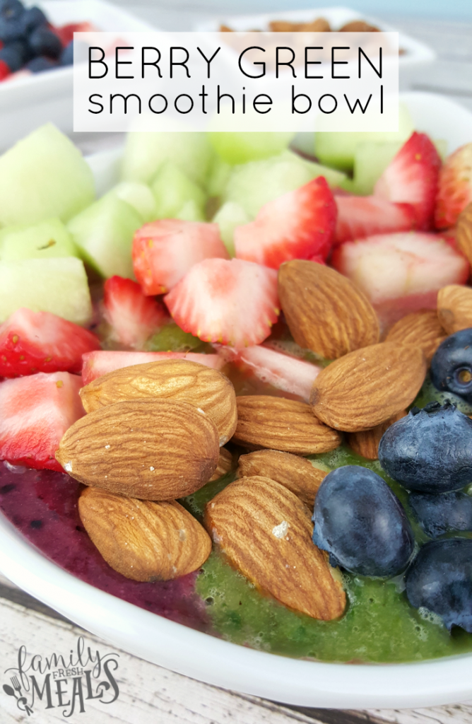 Berry Green Smoothie in a bowl topped with blueberries, strawberries, melon and almonds
