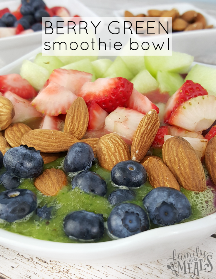 Berry Green Smoothie in a bowl topped with blueberries, strawberries, melon and almonds