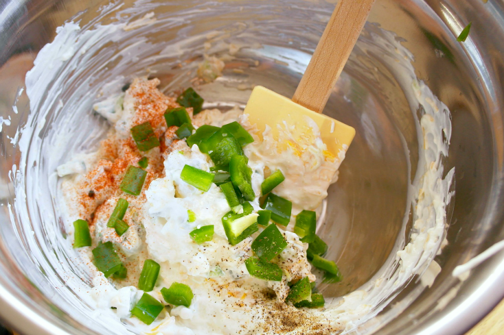 cheese, paprika, salt, pepper and diced jalapeños being added into mixing bowl