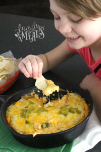 Child scooping dip up with a tortilla chip