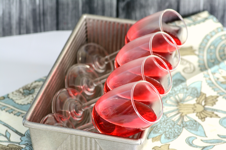 Strawberry Jello in champagne glasses tiled on their sides in a bread pan