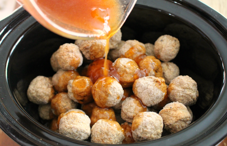 Honey Buffalo Crockpot Meatballs - Frozen Meatballs in crockpot and sauce being poured over the top